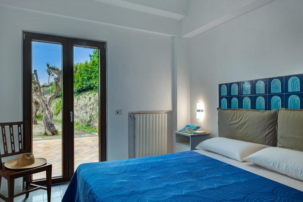 Camera con letto matrimoniale, dettagli blu e portafinestra affacciata sul verde