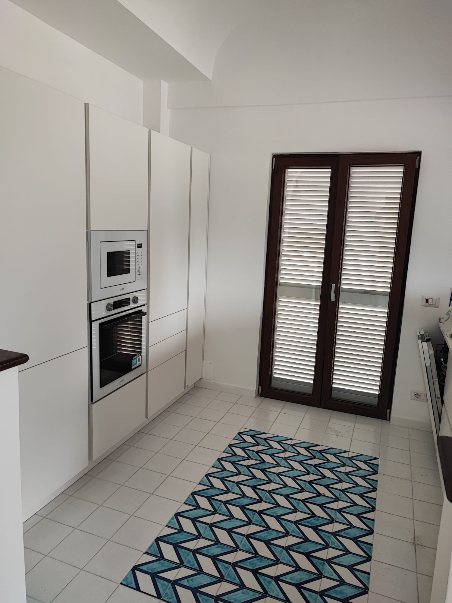 Seconda veduta della cucina con forno, microonde e pavimento decorato