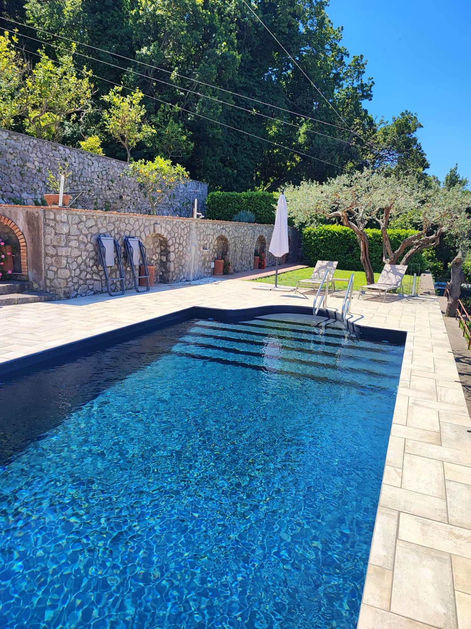La piscina di Villa Demetra, con ulivi e muri in pietra
